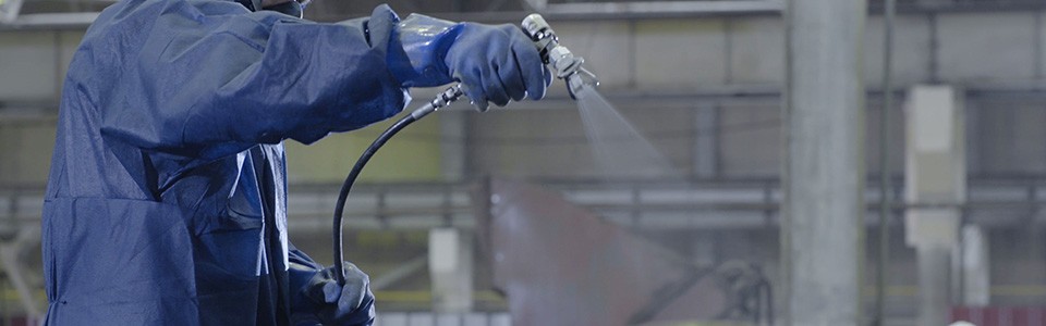 Gloved hand industrial spraying application 1440x450